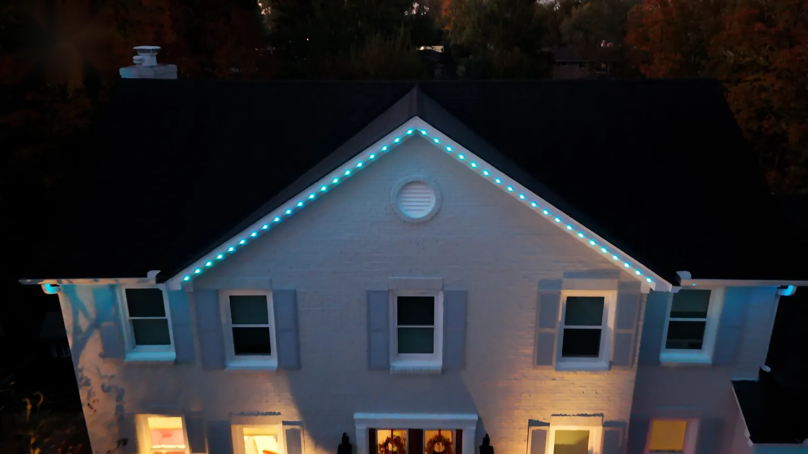 Brick colonial home with white and teal roofline lighting
